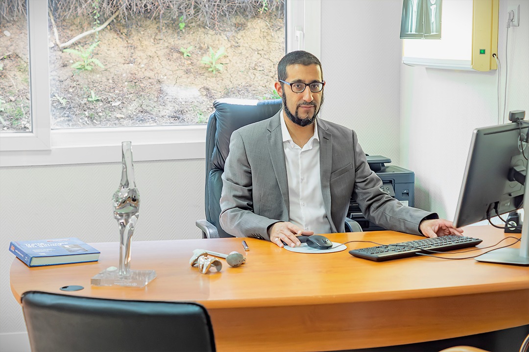 Bureau de consultation du Dr Moussadjy — plan de travail en bois, fauteuil, modèle anatomique et négatoscope