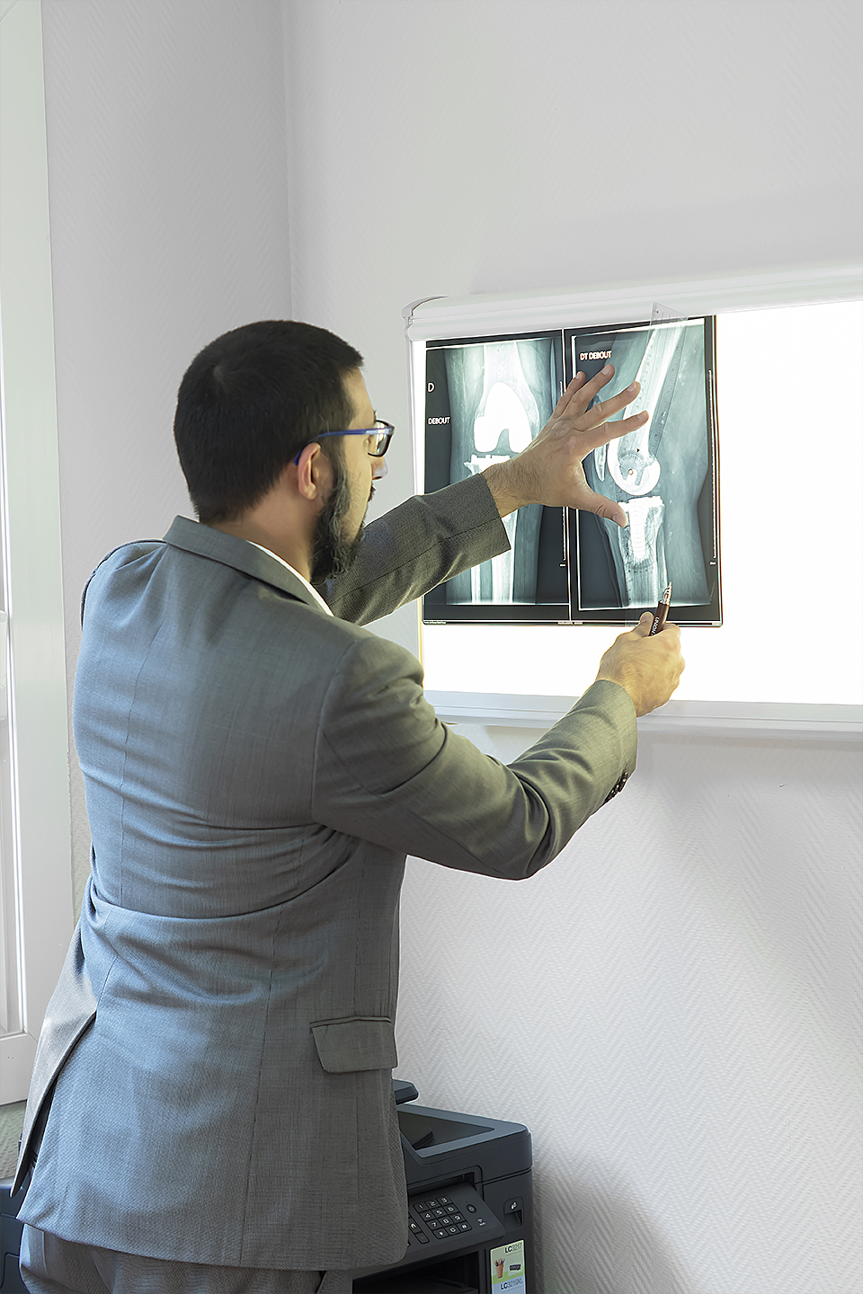 Le Dr Moussadjy pointant une radiographie de genou au négatoscope, expliquant les résultats au patient